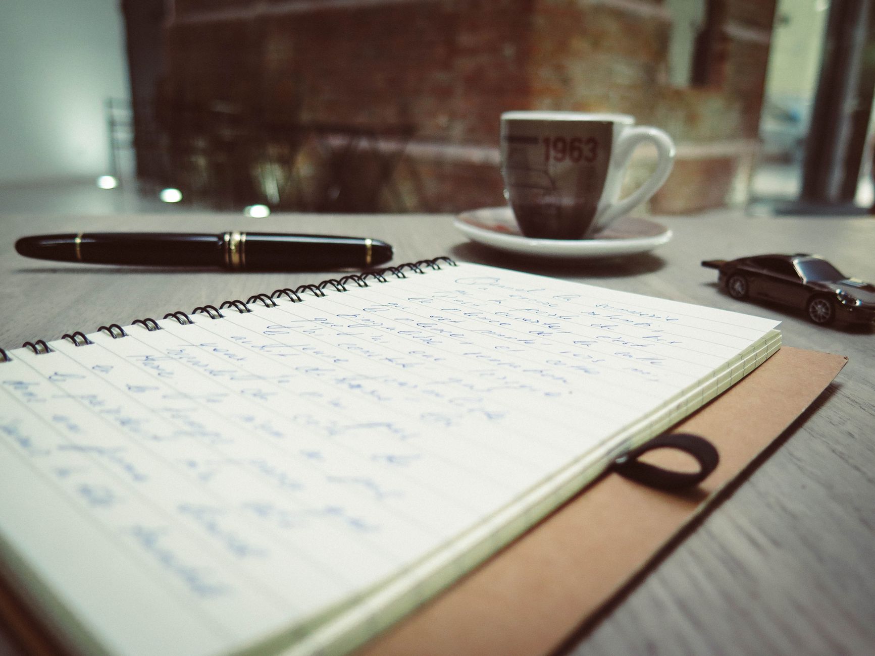Spazio di lavoro accogliente con caffè, appunti scritti a mano e penna sulla scrivania.