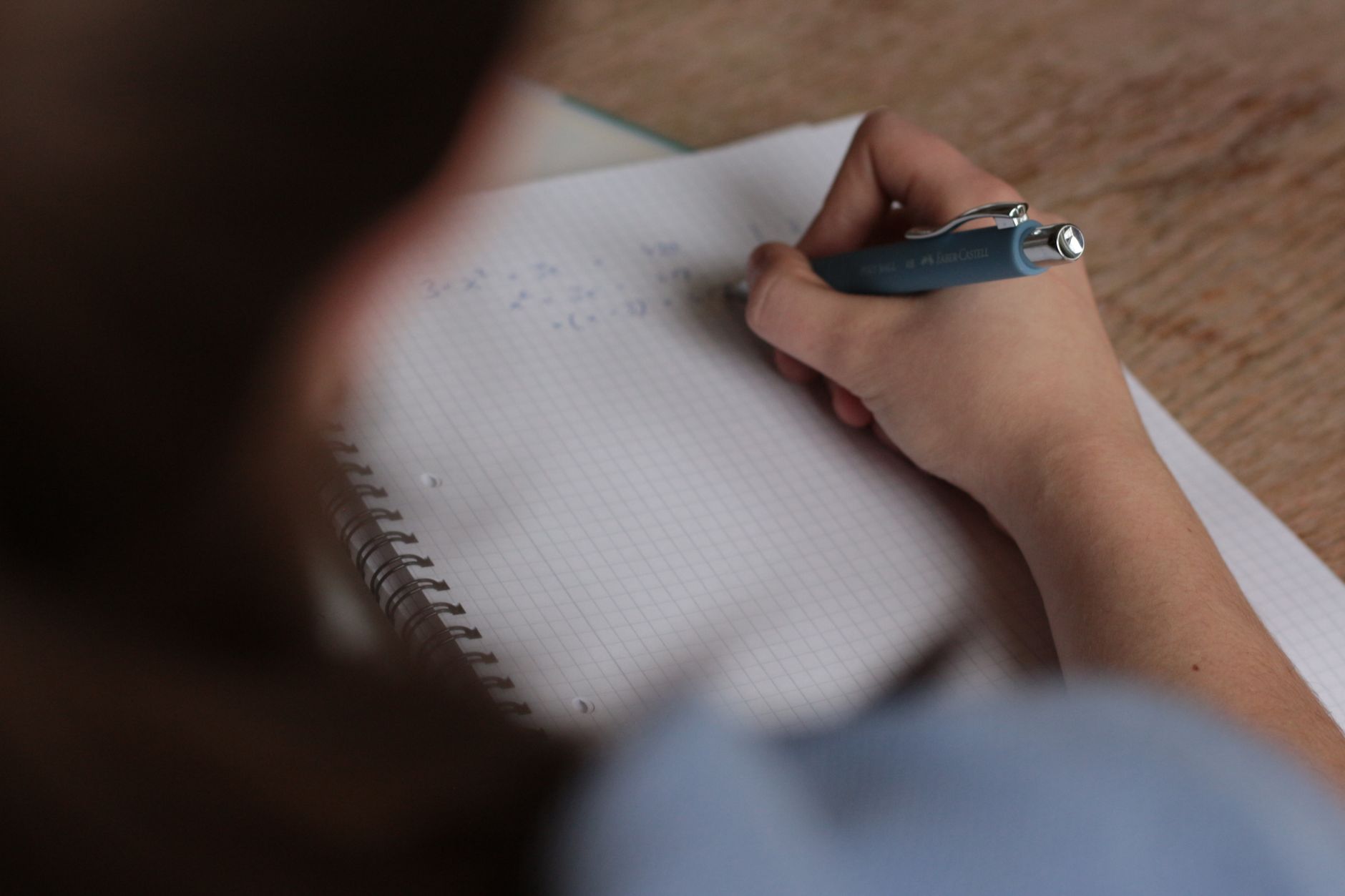 Studente scrive appunti di matematica su un quaderno con una penna.